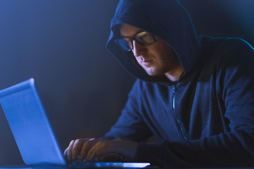 cybercrime, hacking and technology crime - male hacker in dark room using laptop computer for cyber...