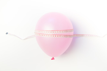 Balloon tied measuring tape on white background. Weight loss, slim body, healthy lifestyle concept. The waist measurement.