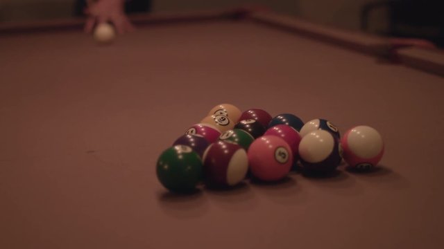 Man hitting the cue ball and breaking on a pool table in 4k.