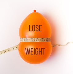 Balloon tied measuring tape on white background. Weight loss, slim body, healthy lifestyle concept. The waist measurement.