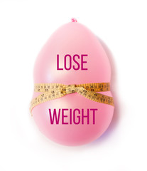 Balloon tied measuring tape on white background. Weight loss, slim body, healthy lifestyle concept. The waist measurement.