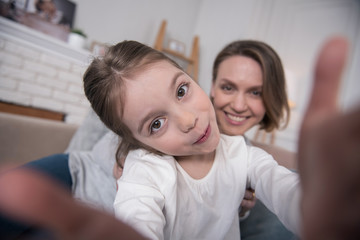 Photographing. Beautiful content mummy and daughter smiling and taking selfies