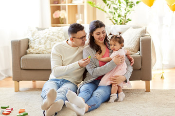 family and people concept - happy mother, father and little daughter at home