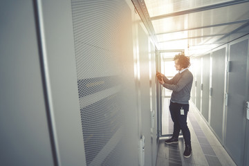 male technician inspecting and working on servers in server room