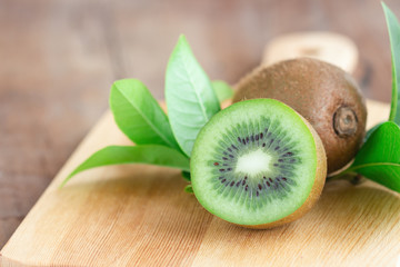 Fresh and juicy kiwi fruit and a half on cutting board on wood table in side view with copy space for background or wallpaper. Kiwi have sweet and sour taste and have high vitamin c and antioxidant.