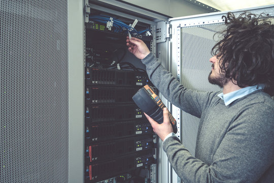 male technician inspecting and working on servers in server room