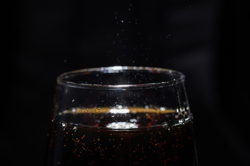 A glass of cola drink with a salt close-up.