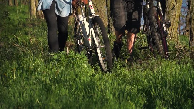 Slow-motion shooting, a couple of cyclists walking through the fores