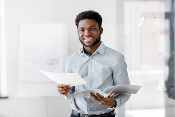 business, people and corporate concept - smiling african american businessman with folder at office