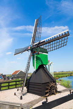 Dutch typical landscape. Traditional old dutch windmill against blue cloudy sky in the Zaanse Schans village, Netherlands. Famous tourism place.