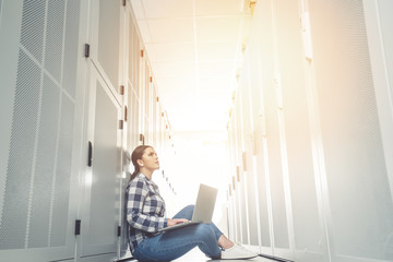 Woman technician working on and inspecting servers in server room