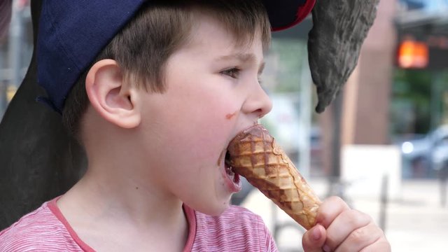 Boy portrait licking eating ice cream on a street public place