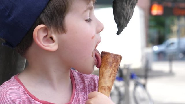 Boy portrait licking eating ice cream on a street public place
