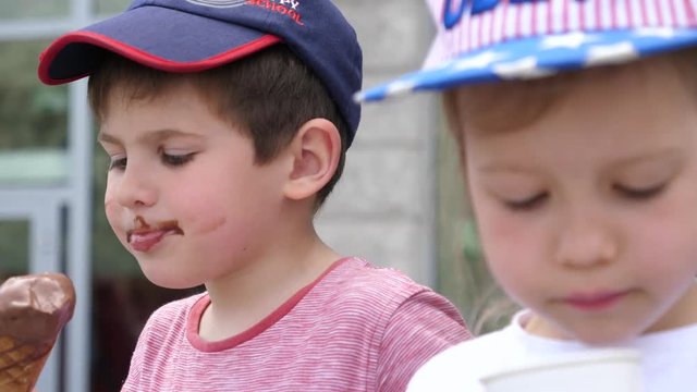 Little boy and girl children funny licking eating ice cream on a street public place
