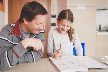 Young caucasian girl studying, doing homework with father
