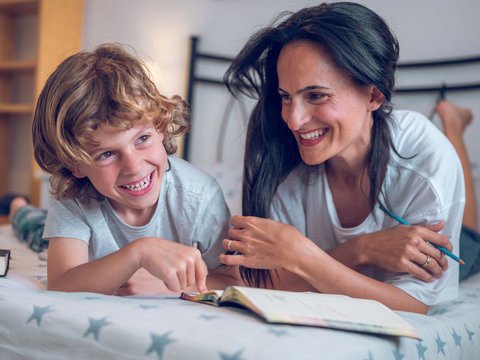 Smiling mother and son lying on bed
