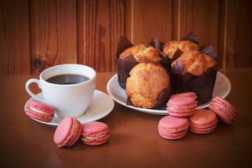 Coffee, macaroons and muffins on wooden table. Selective focus.