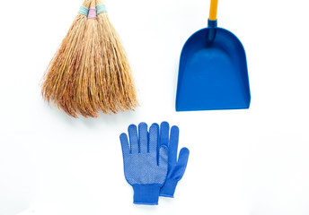 Minimalist cleaning composition on white background. Fabric gloves, broom and scoop. Flat lay