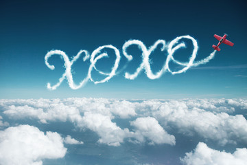 XOXO word created from a trail of smoke by Acrobatic plane.