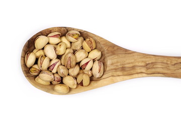 Pistachios in wooden spoon isolated on white background, top view