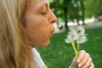 Woman blowing a dandelion.