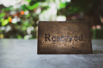 rough metal reserved sign on dining table in restaurant, beautiful bokeh as background