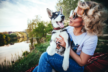 blonde in glasses and with earrings in the form of a treble clef smiles and looks at a small Husky...