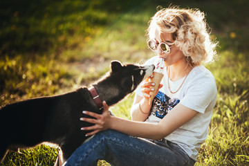 joyful blonde in a white t-shirt with  husky eat ice cream on a meadow in the park in the summer