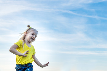 portrait of a cheerful little girl in full growth against a blue sky. Concept freedom
