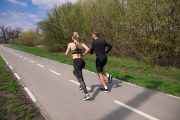 Do not stop! Two young strong-muscled athletic runners training outdoors and working out, while running around the stadium.