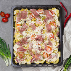 Preparation Potatoes with meat, vegetables and greens with cream sauce on a roasting dish. Flat lay.