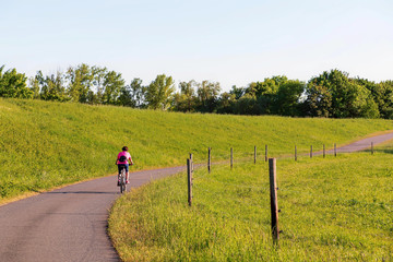 Obraz premium A cyclist rides along the dike in the sunlight