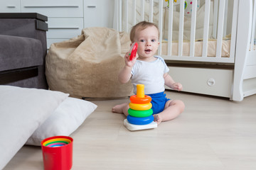 Cute toddler boy in pajamas playing on floor at bedroom