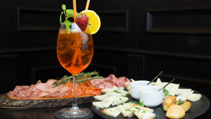 Traditional italian aperitif with proscioutto, mortadella sausage, cheese and aperol spritz drink