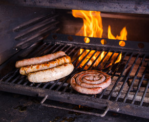 Grilled sausage on the flaming grill. BBQ with fiery background, close up