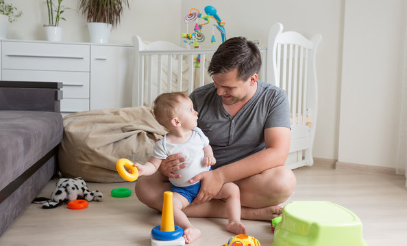 Happy young man sitting on floor with his baby boy