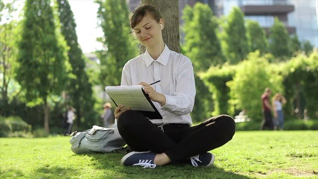 Young business woman/student doing her tasks in the park.