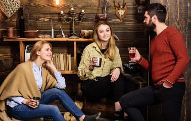 Family enjoy conversation in gamekeepers house. Friends, family spend pleasant evening, interior background. Sincere conversation concept. Girls and man on happy faces hold metallic mugs, talking
