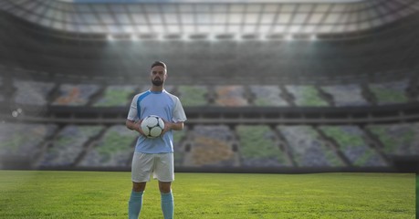 Soccer player holding football in stadium