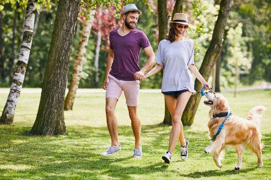 Young couple running and playing with their dog while out on a walk