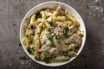 Italian pasta penne with chicken meat and bacon on plate