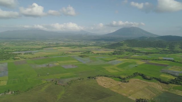 Mountain valley with farmland, rice terraces near mount Iriga. Aerial view mount with green tropical rainforest, trees, jungle with sky. Philippines, Luzon. Tropical landscape