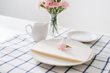 Table setting with dishes, cutlery and flowers on white background