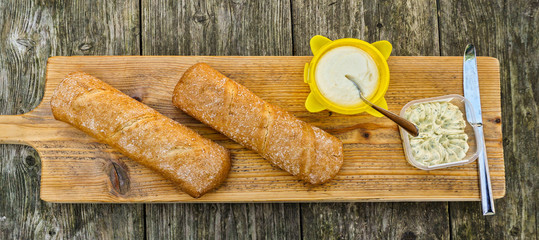 Gluten-free bread loaves/rolls. Top down view on rustic wooden cutting board outdoors at barbecue.