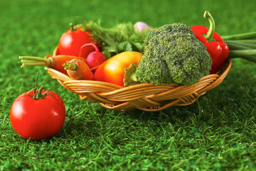 Assortment of fresh fruits and vegetables in a basket on the grass