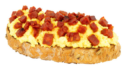 Scrambled eggs with diced chorizo salami on toast isolated on a white background