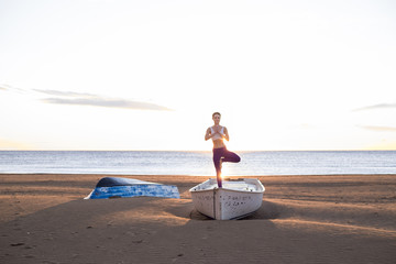 chica al amanecer practicando yoga sobre barca