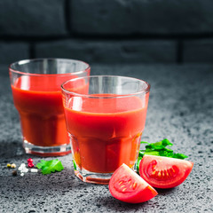 Fresh tomato juice in glasses on dark concrete background. Selective focus, space for text.