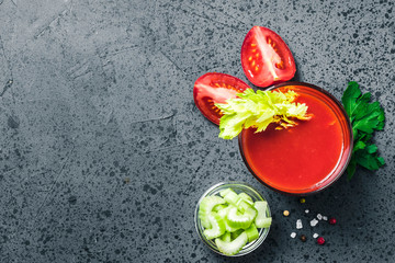 Celery tomato juice in glasses on dark concrete background. Top view, space for text.