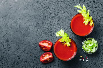 Celery tomato juice in glasses on dark concrete background. Top view, space for text.